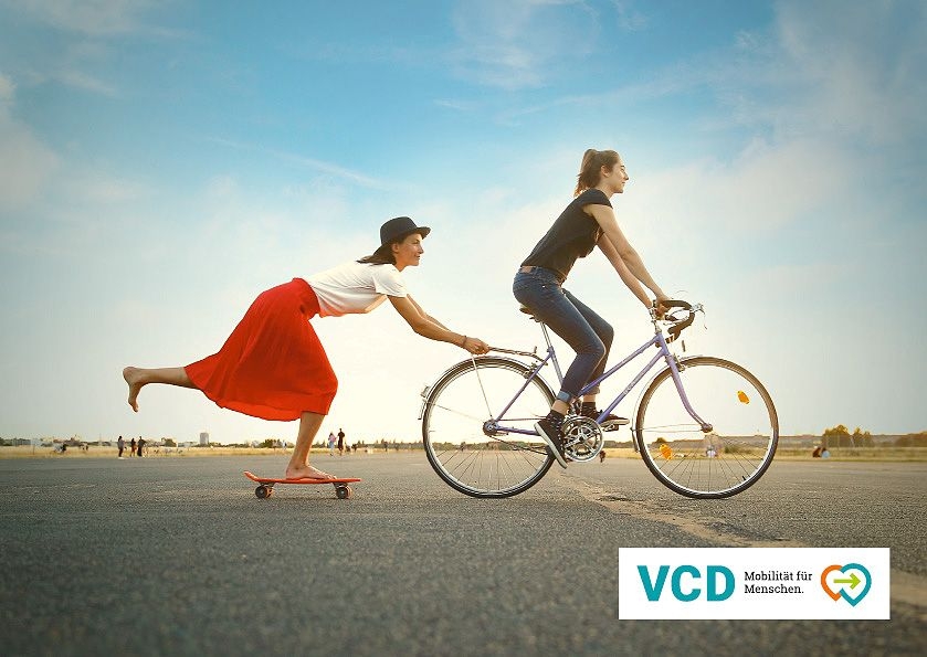Zwei Frauen auf Fahrrad und Skateboard